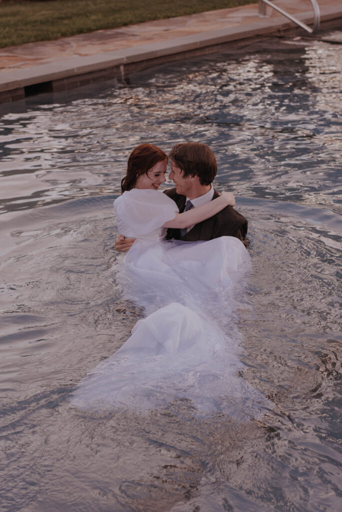 groom carries bride out of pool