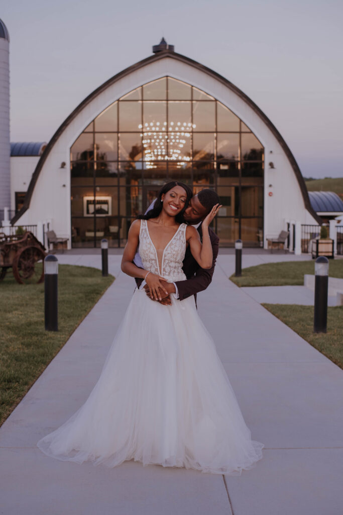 bride and groom posed outside the entrance of the Barn at Brambleton in Northern Virginia