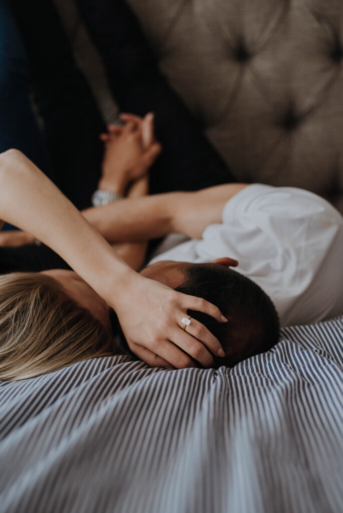 Couple snuggling on bed with rings